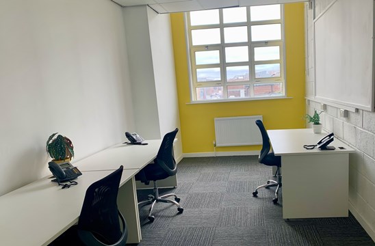 Yellow feature wall with windows. Desks and chair